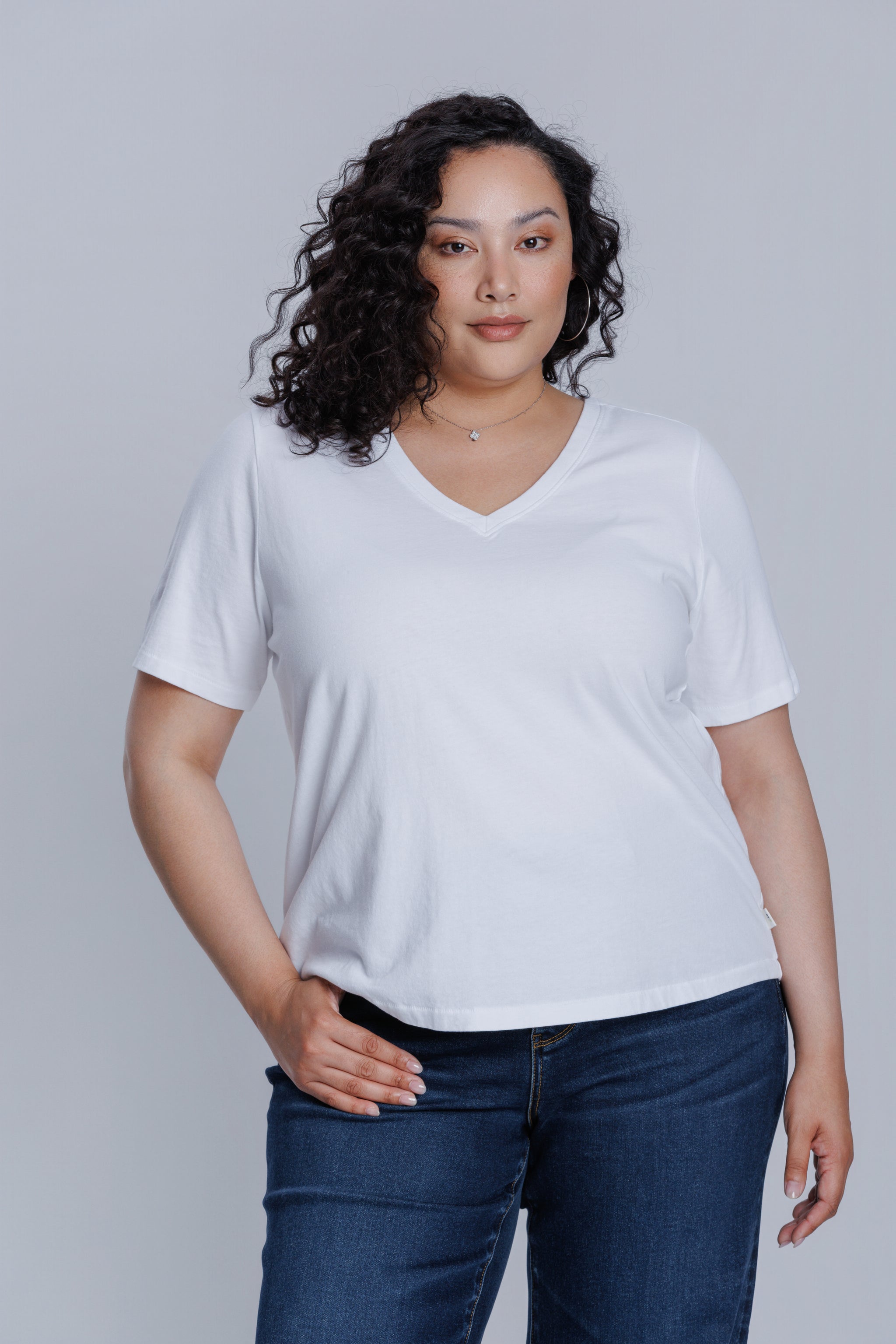 Woman wearing a DePart white t-shirt and dark blue wide leg jeans against a light gray background | model-size: 16