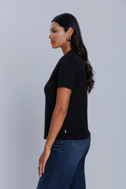 Woman wearing a DePart black t-shirt and dark blue wide leg jeans against a light gray background