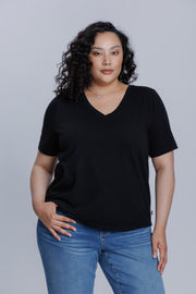 Woman wearing a DePart black t-shirt and blue straight jeans against a light gray background | model-size: 16