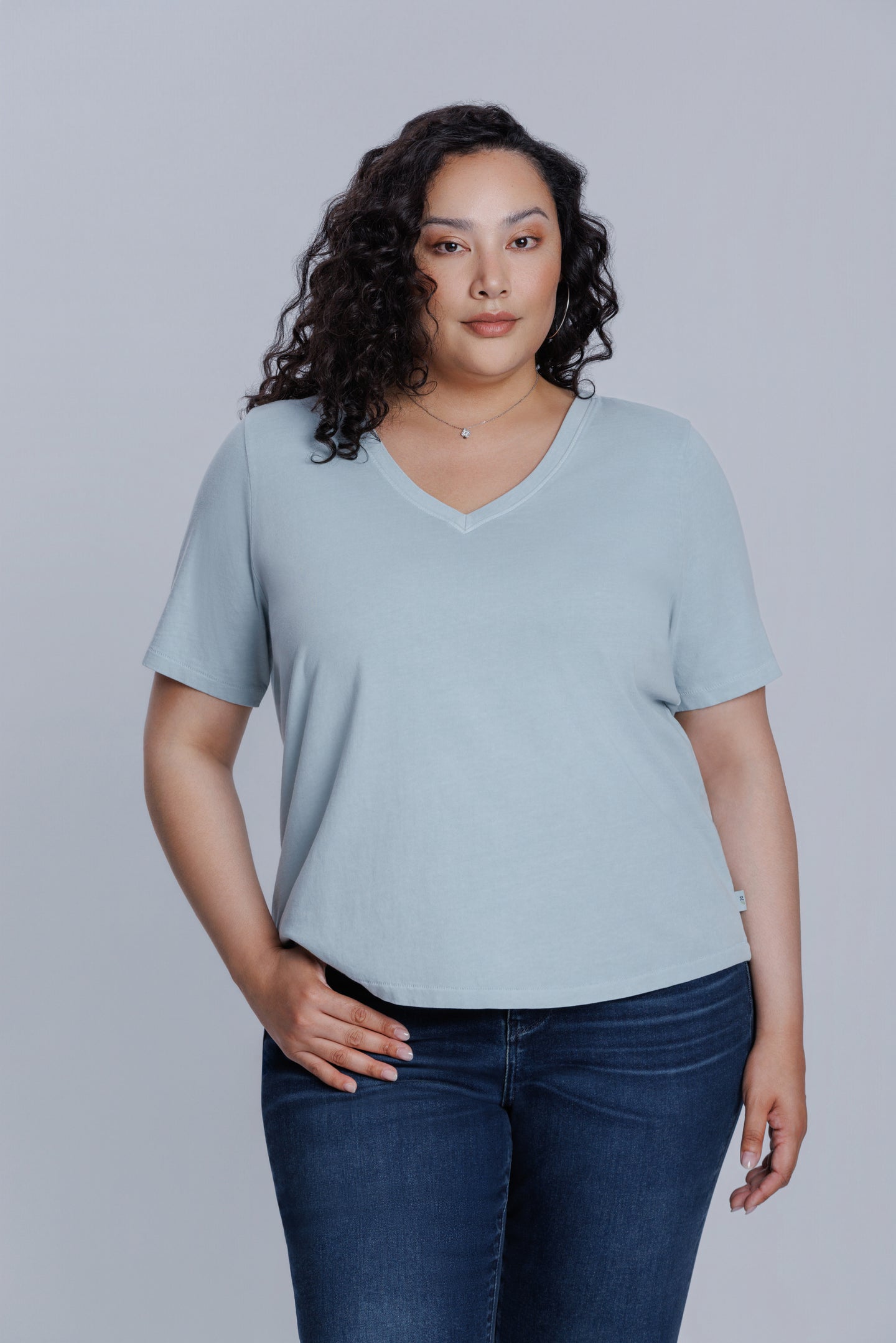Woman wearing a DePart light blue t-shirt and dark blue straight jeans against a light gray background | model-size: 16