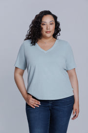 Woman wearing a DePart light blue t-shirt and dark blue straight jeans against a light gray background | model-size: 16