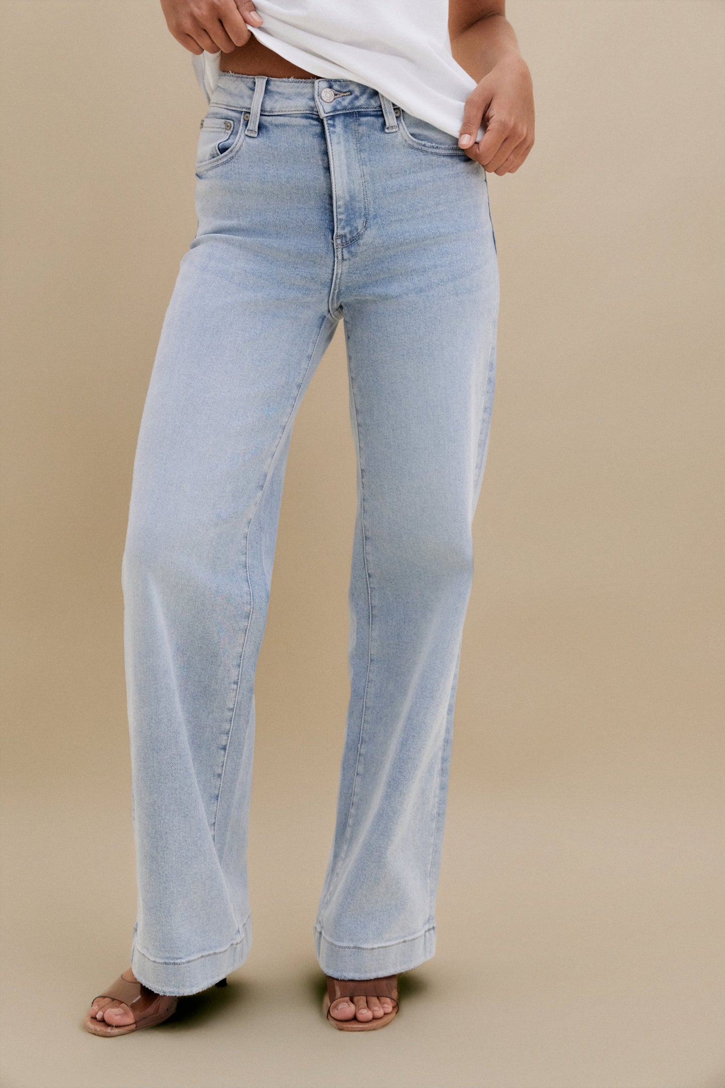 Light blue jeans worn by a person on a beige background