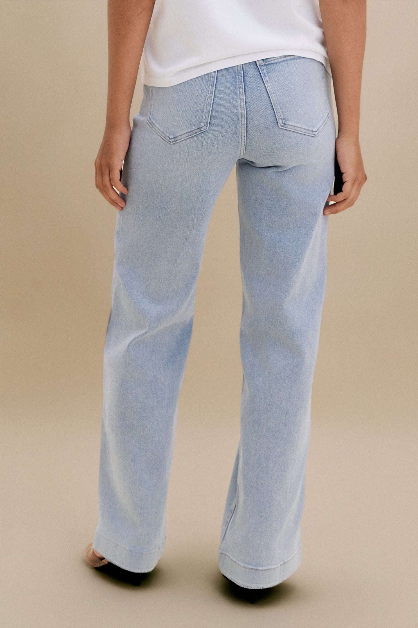 Light blue jeans worn by a person on a beige background