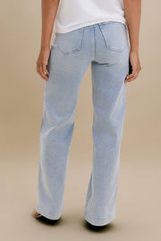 Light blue jeans worn by a person on a beige background