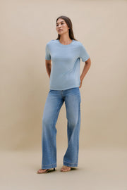 Woman wearing a light blue t-shirt and jeans against a beige background | model-size: 4