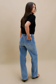 Woman wearing blue jeans and a black top on a beige background