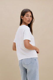 Woman wearing a plain white t-shirt and blue jeans against a beige background