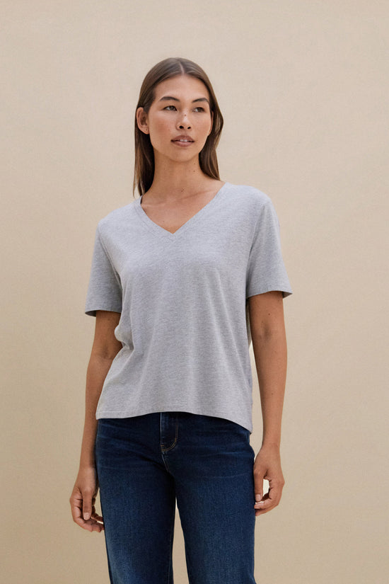 Woman wearing a gray t-shirt and blue jeans against a beige background | model-size: 4