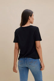 Person wearing a black t-shirt and blue jeans on a beige background