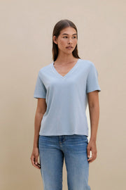 Woman wearing a blue t-shirt and jeans on a beige background | model-size: 4