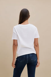 Woman wearing a plain white t-shirt and blue jeans against a beige background 