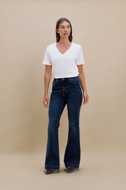 Woman wearing a plain white t-shirt and blue jeans against a beige background 
