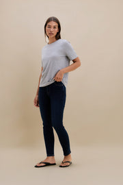 Woman wearing a gray t-shirt and dark jeans on a beige background