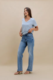 Woman wearing a light blue t-shirt and jeans against a beige background