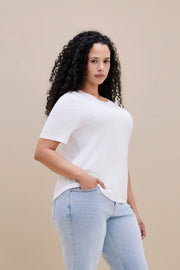 Woman wearing a white t-shirt and light blue jeans against a beige background