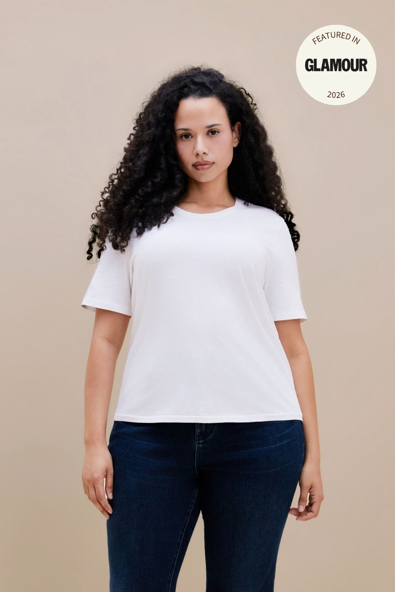 Women wearing a plain white t-shirt and dark jeans with a GLAMOUR logo | model-size: 16
