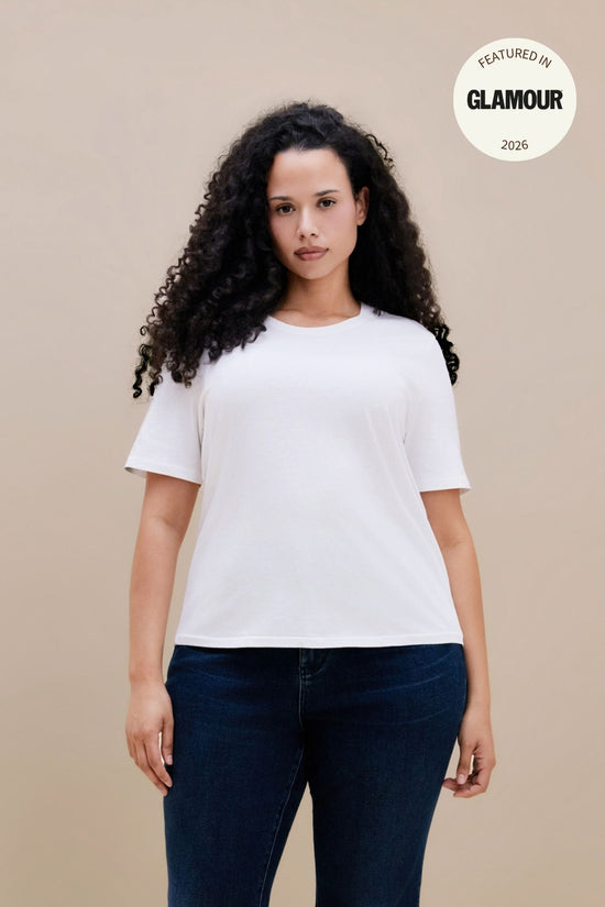 Women wearing a plain white t-shirt and dark jeans with a GLAMOUR logo | model-size: 16