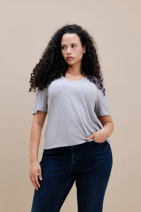 Woman wearing a heather grey v-neck t-shirt and dark jeans | model-size: 16