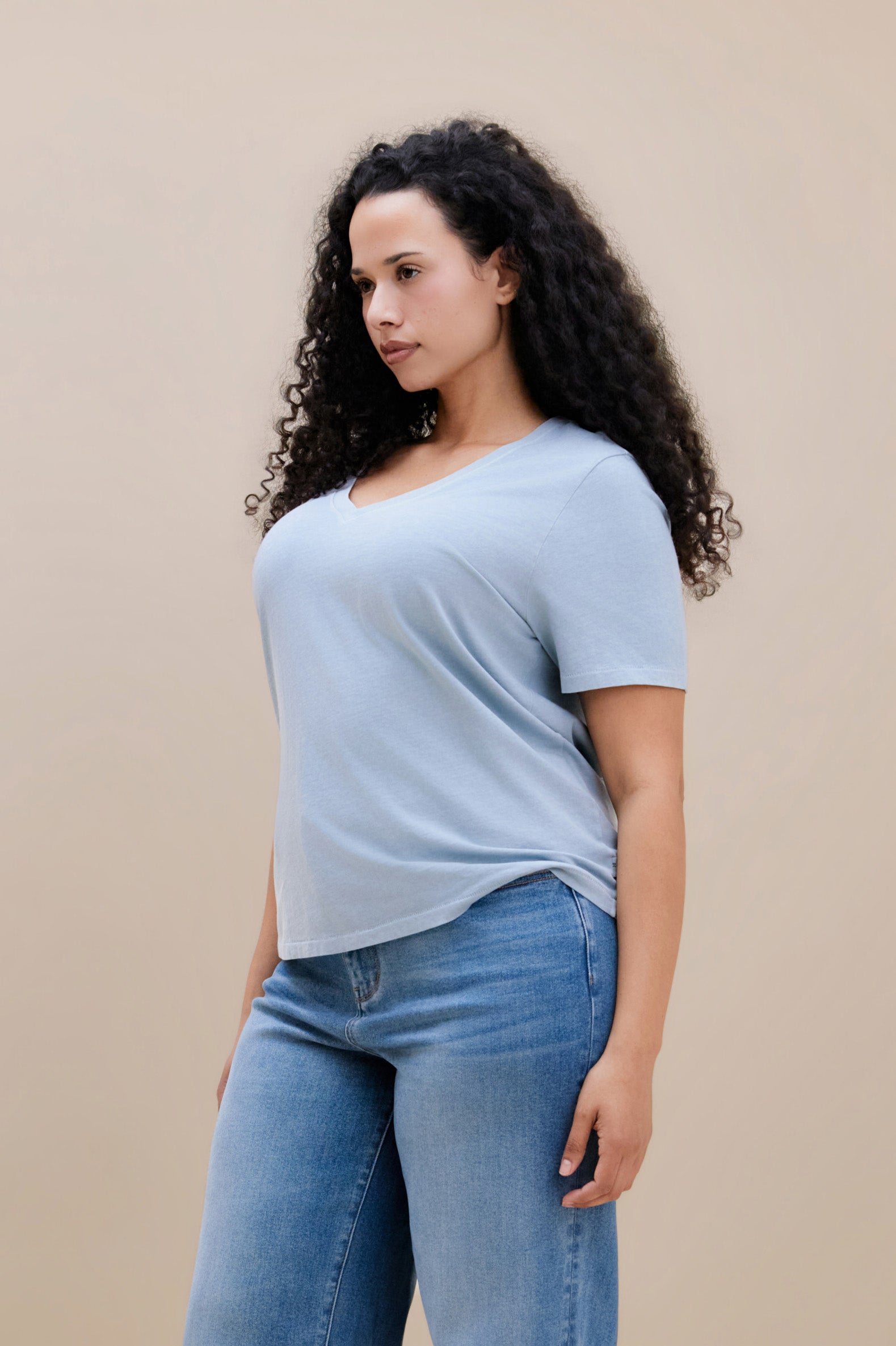 Woman wearing a blue t-shirt and jeans with a beige background
