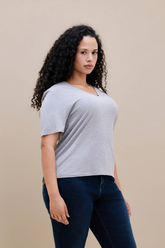 Woman wearing a heather grey v-neck t-shirt and dark jeans
