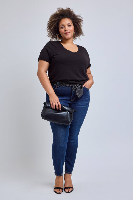 Woman wearing a black t-shirt and blue jeans with a black handbag on a white background | model-size: 16