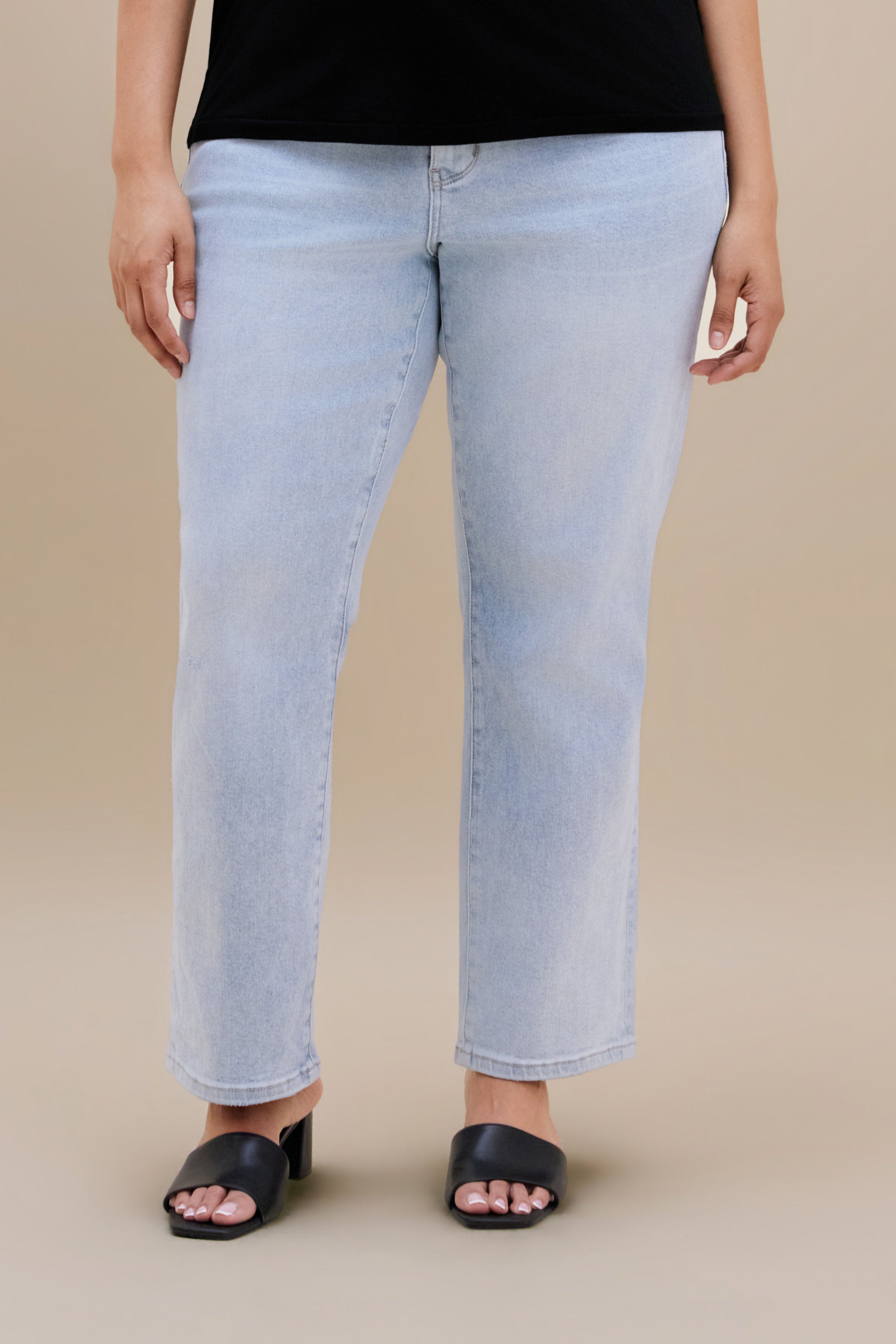 Bottom close up of light slim jeans against a beige background