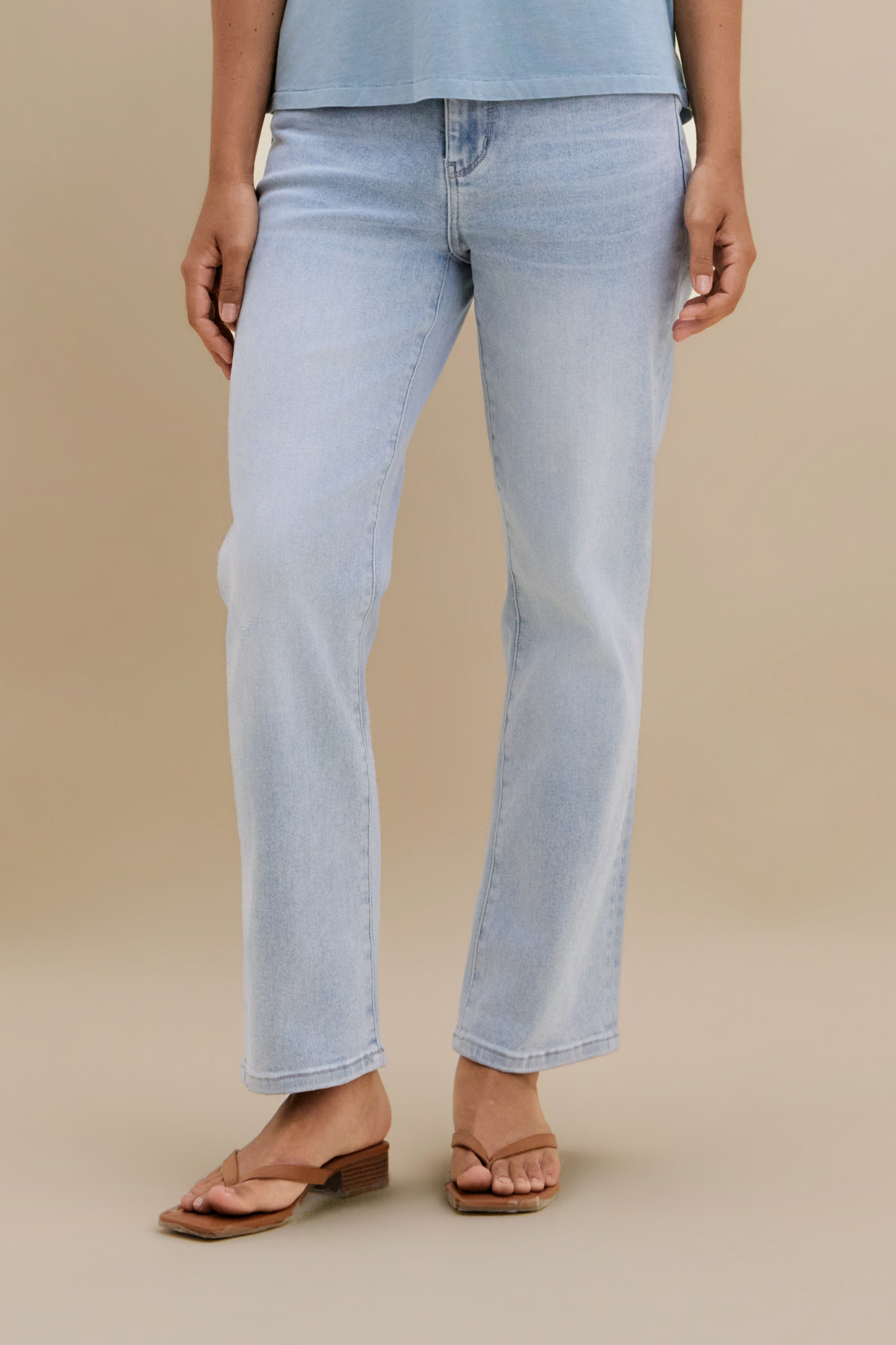 Bottom close up of light slim jeans against a beige background