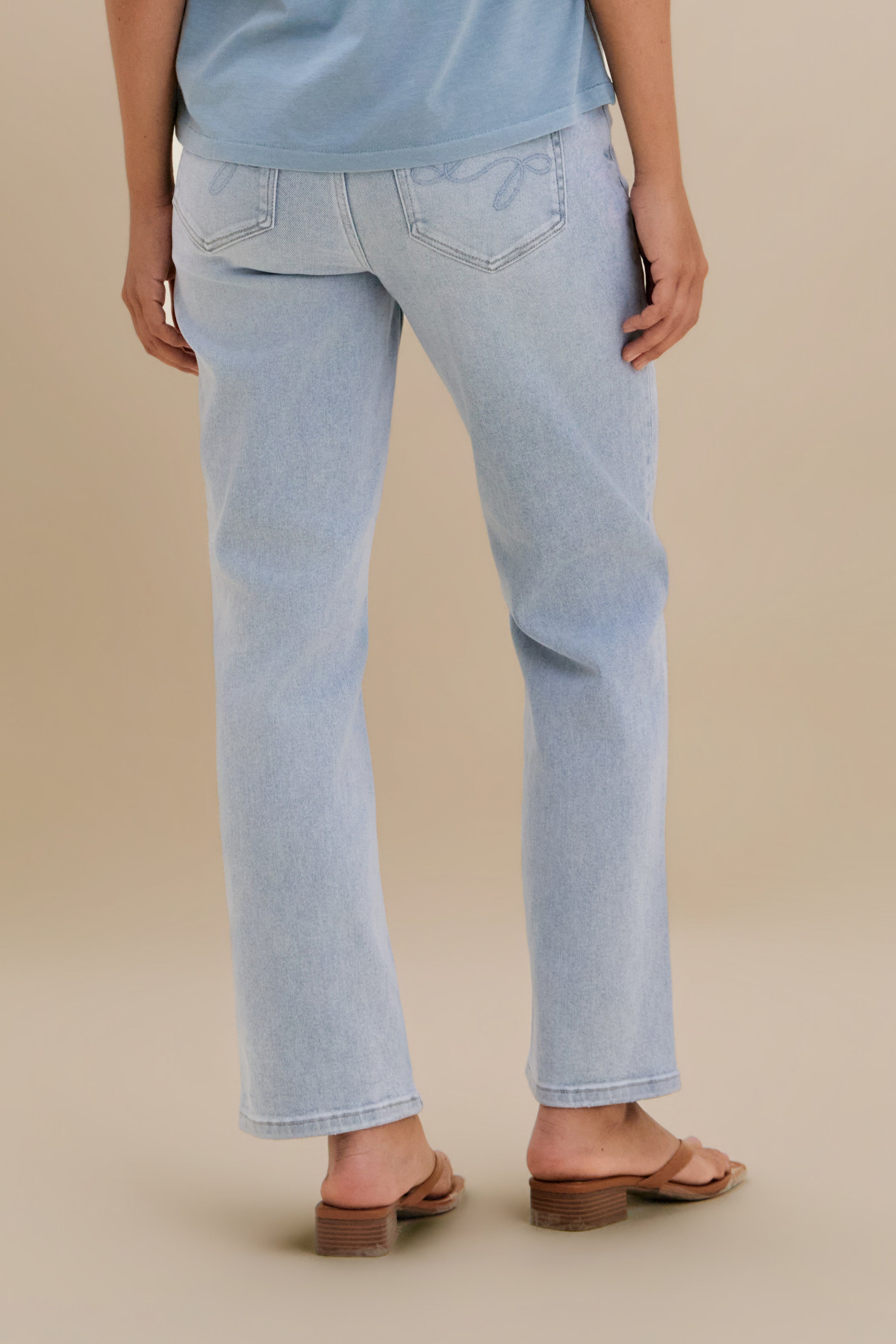 Bottom close up, backside, of light slim jeans against a beige background