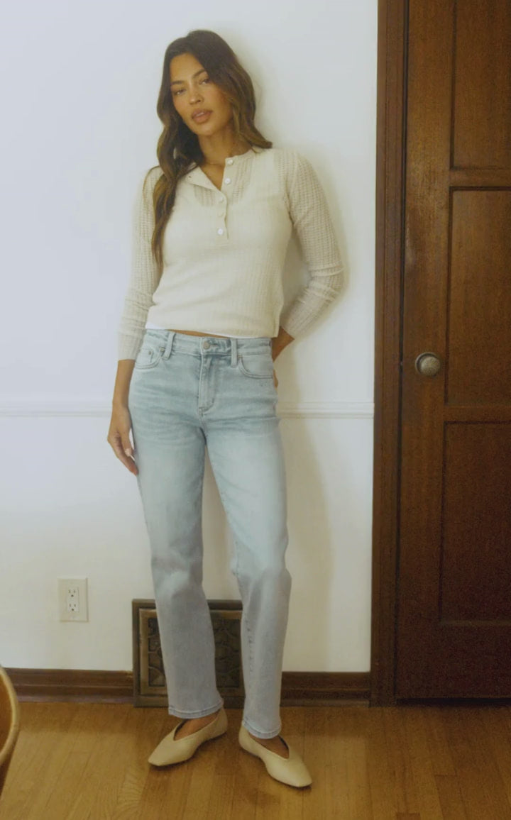 Woman in motion walking through a house wearing light colored denim jeans.