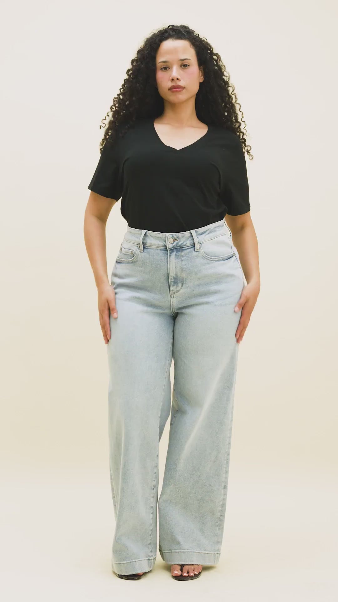 Video of a woman wearing wide leg jeans in a light wash with a black t-shirt