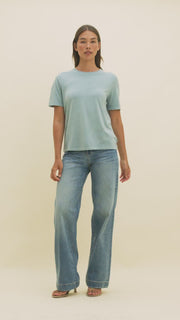 Video of a woman wearing medium wash wide-leg jeans and a light blue t-shirt