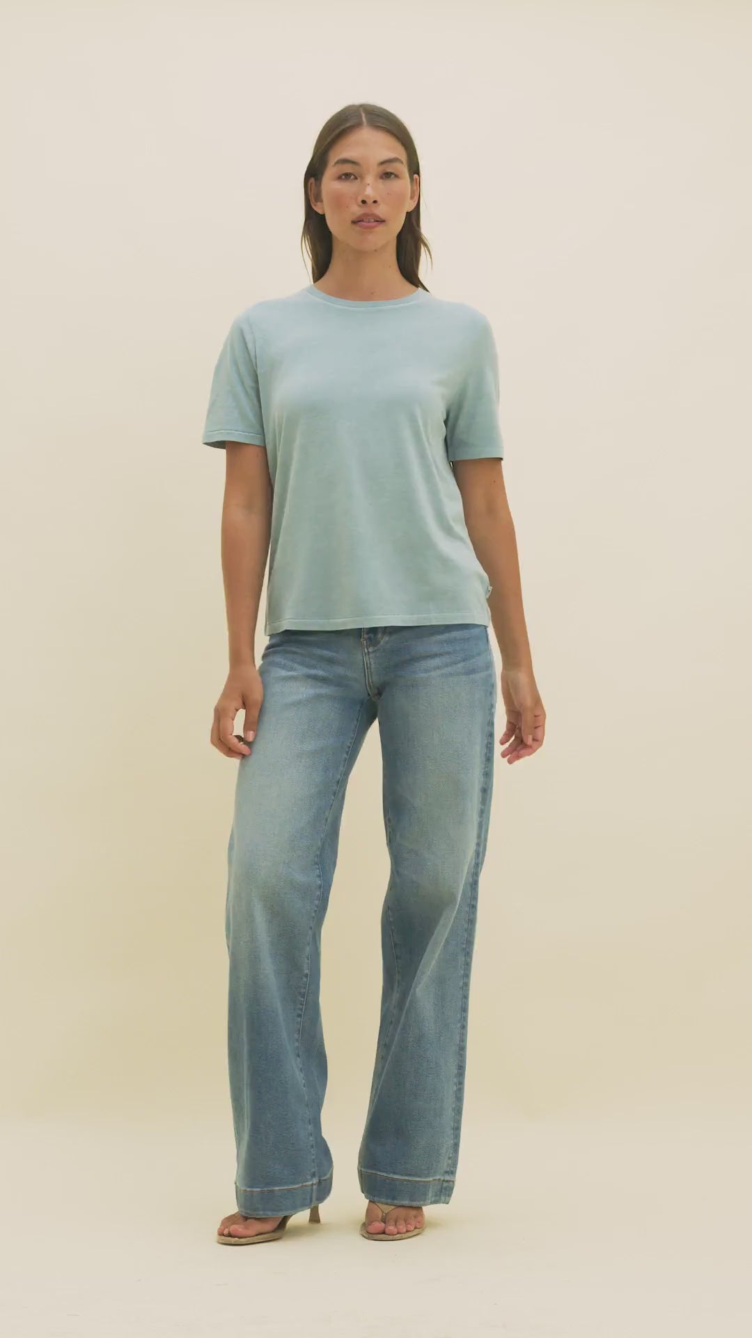 Video of a woman wearing medium wash wide-leg jeans and a light blue t-shirt