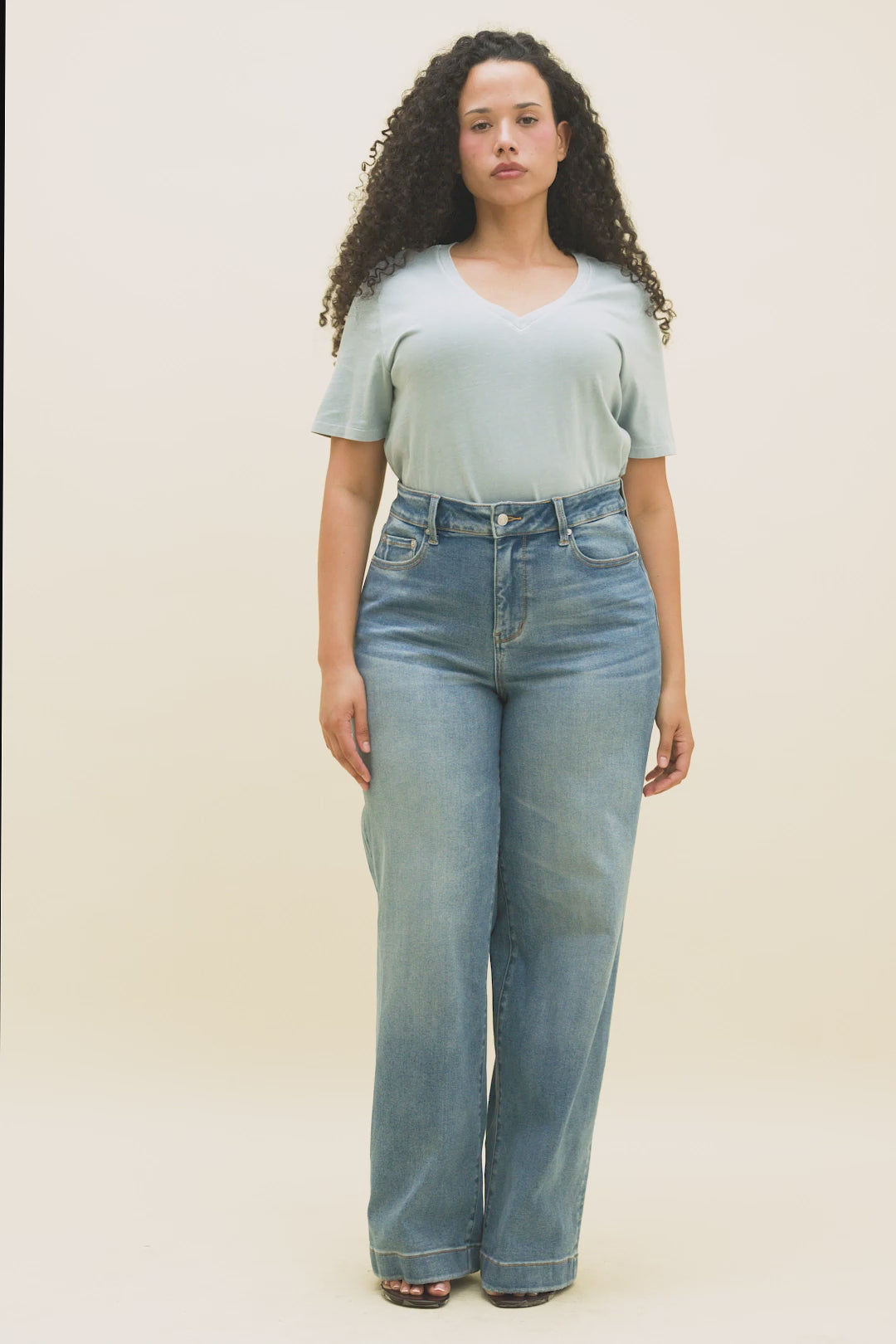 Video of a woman wearing a light blue v-neck t-shirt and medium blue wide leg jeans.