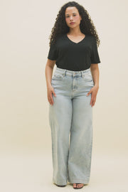 Video of a woman wearing a black v-neck t-shirt and light blue wide leg jeans.
