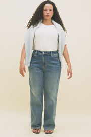 Video of a woman wearing a white t-shirt and blue jeans with a light blue sweater draped over her shoulders.