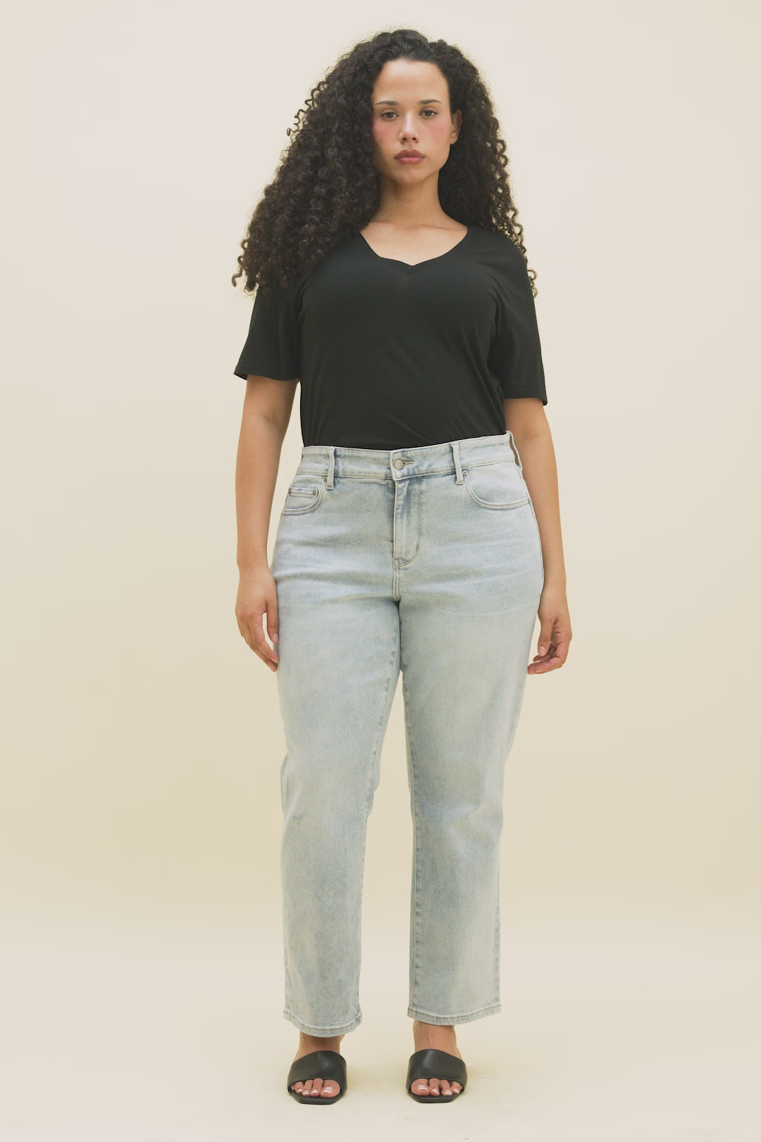 Video of a woman wearing a black v-neck t-shirt and light blue straight jeans.