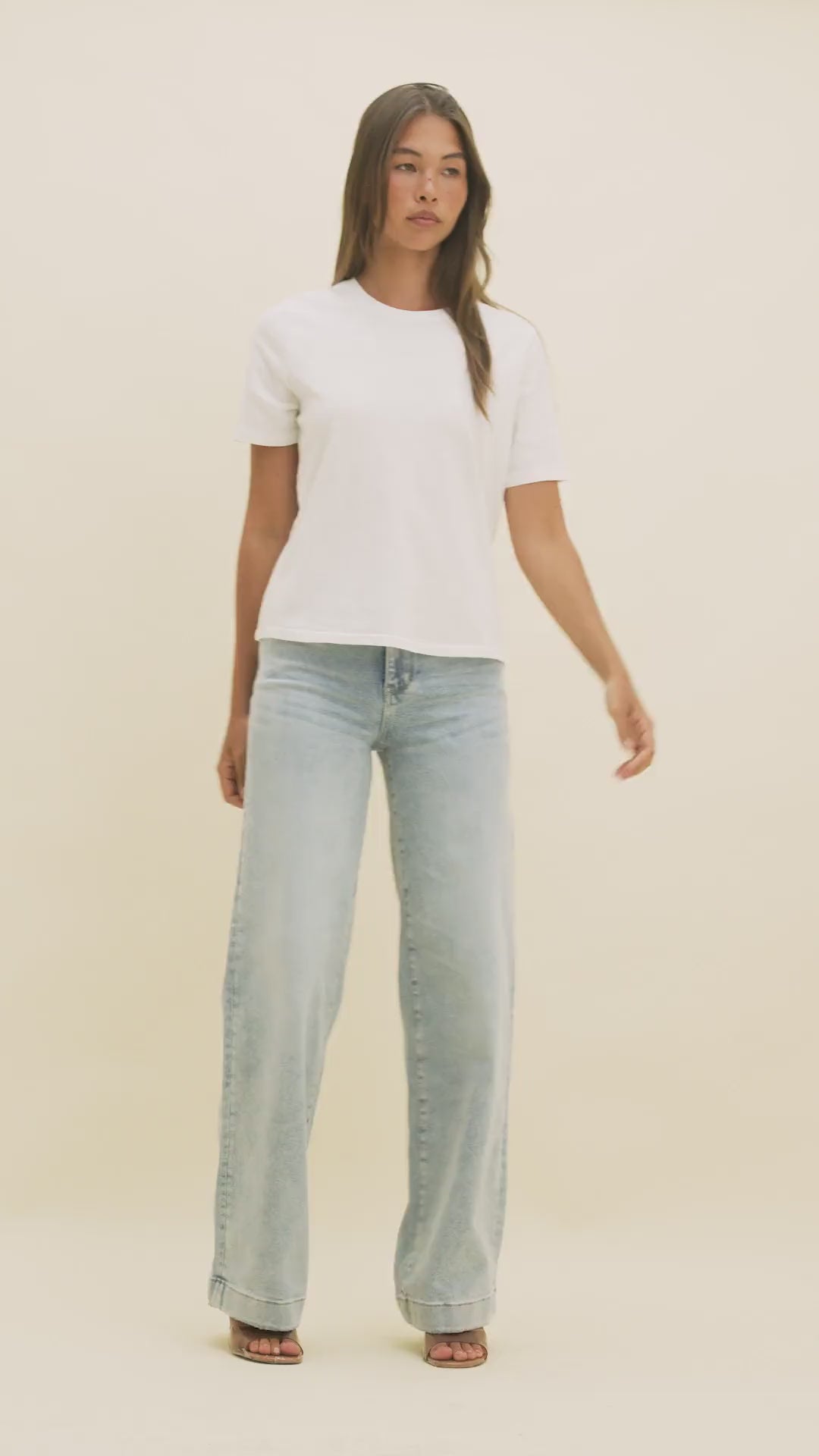 Video of a woman wearing light colored wide-leg jeans and a white t-shirt