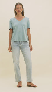 Video of a woman wearing light colored straight leg jeans and a light blue t-shirt