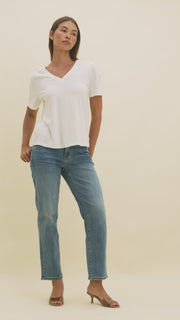 Video of a woman wearing medium wash straight cropped jeans and a white v-neck t-shirt
