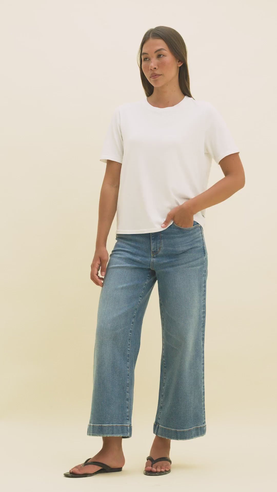 Video of a woman wearing medium wash wide-leg ankle jeans and a white crew neck t-shirt