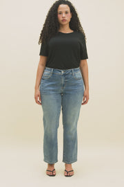 Video of a woman wearing a black t-shirt and medium blue cropped straight leg jeans.